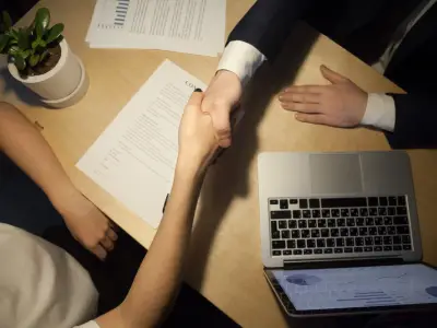 Top view close up shot of an interviewer and an UI/UX design candidate shaking hands